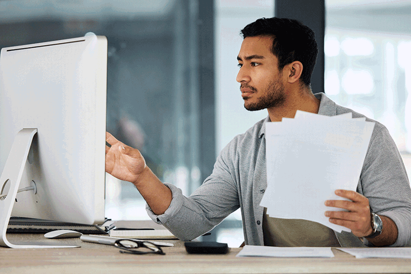 Man looking at computer with papers